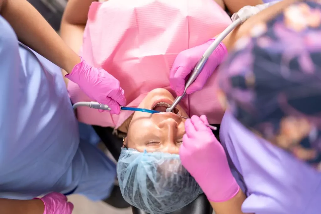 In the serene and holistic environment of our Tulsa, Oklahoma dental practice, a patient is receiving attentive care from a health-focused dentist and her dedicated assistant. Both professionals, embodying our commitment to compassionate healthcare, are wearing pink gloves as they deliver treatment centered on overall well-being and oral health harmony.