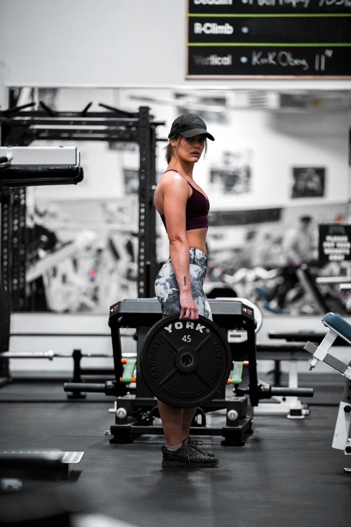 An individual attired in athletic wear is engaging in a holistic fitness regimen, expertly lifting a barbell integrated with weights within a supportive environment enriched by state-of-the-art wellness equipment and inspiring health-focused affirmations. Located in Tulsa, Oklahoma, this setting emphasizes the synergy between physical strength and overall well-being.